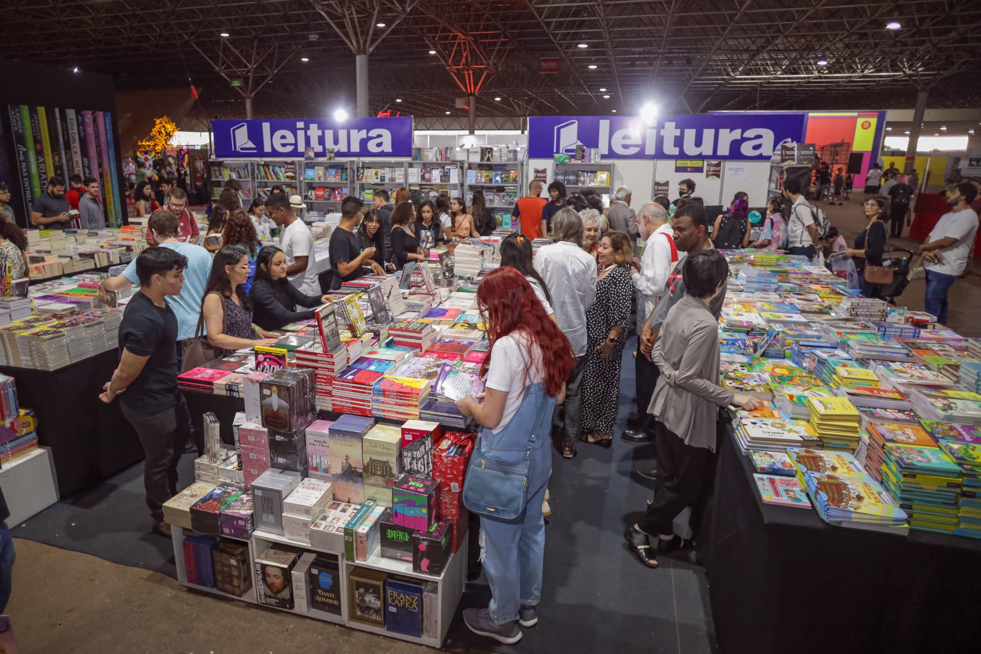 Visitantes escolhendo livros nos estandes das livrarias da BILB
